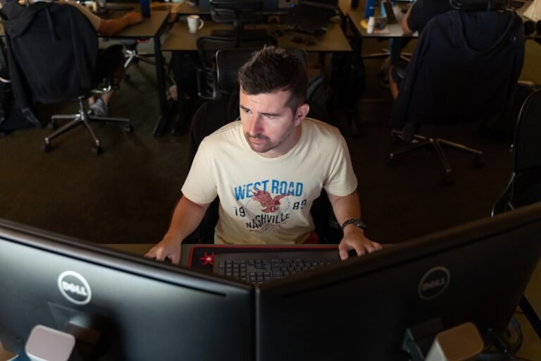 Um Homem Sentado Na Frente De Um Monitor De Computador u_JVHBXrseA