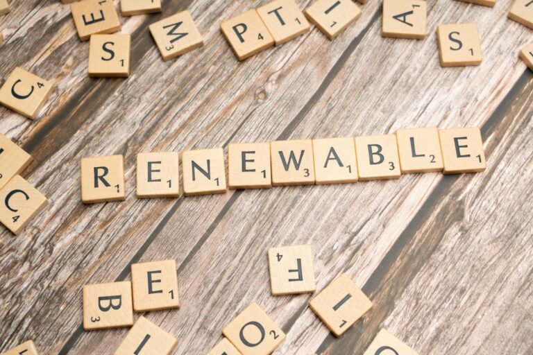Wooden Scrabble tiles on a wooden table spell 'Renewable' emphasizing sustainability.