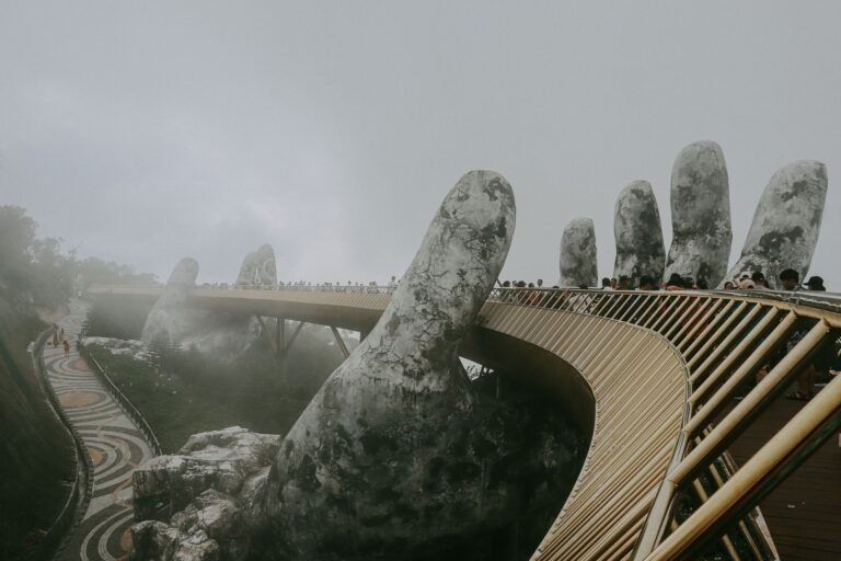 Stunning view of Golden Bridge held by stone hands enveloped in mist, Ba Na Hills.