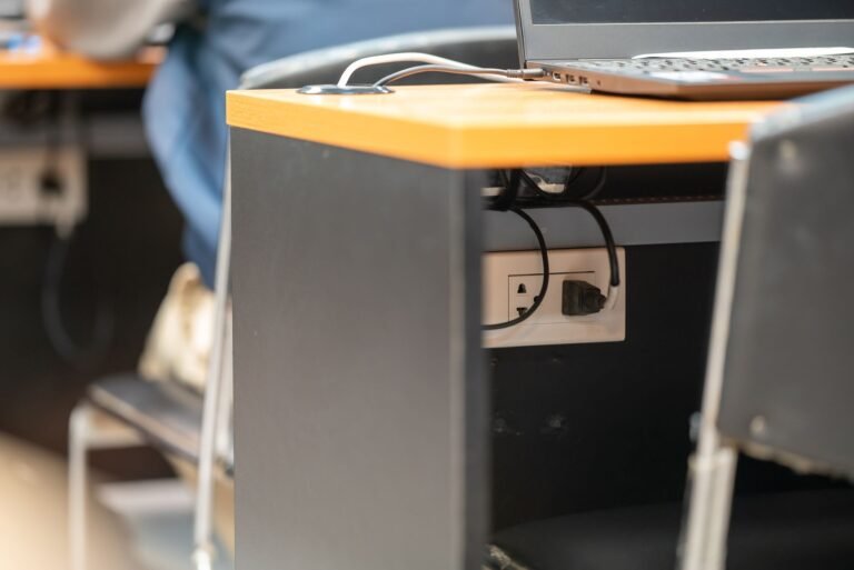 A clean office workspace featuring a desk, laptop, and hidden power cord management.